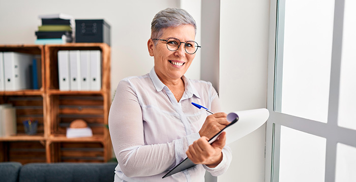 Mujer mayor de 50 años sonriente con una planilla en sus manos