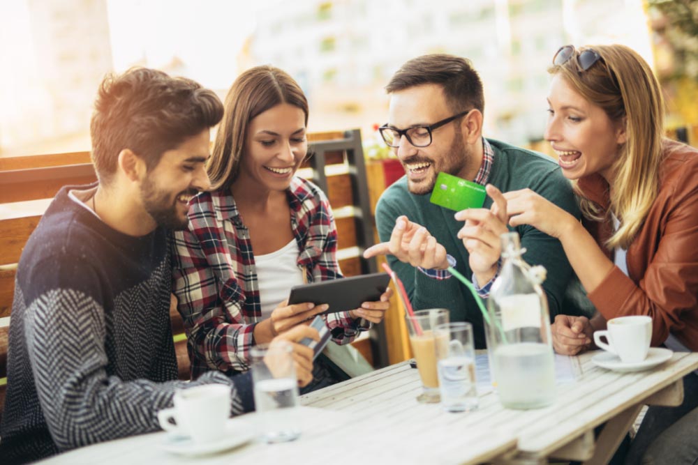 Jóvenes felices comprando con su tarjeta de crédito de banco Popular