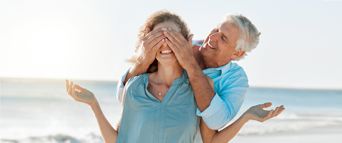 Hombre cubriendo los ojos de una mujer frente al mar