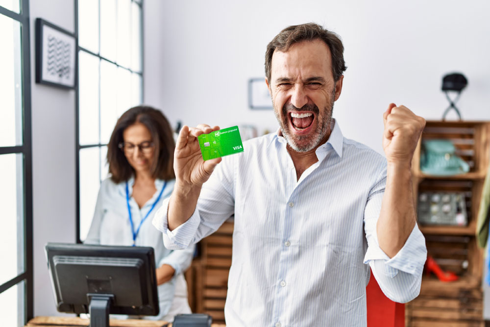 Hombre feliz con su tarjeta de crédito de banco Popular