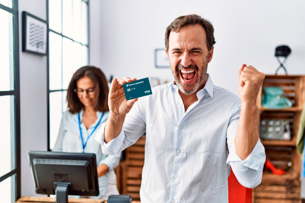 Hombre feliz con su tarjeta de crédito de banco Popular