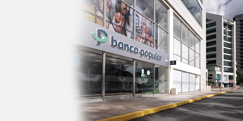 oficinas del Banco Popular con vidrios de cristal y letrero verde con logotipo blanco