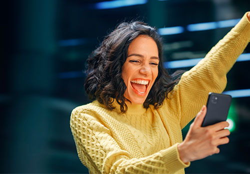 Imagen de mujer sonriendo con un celular en la mano