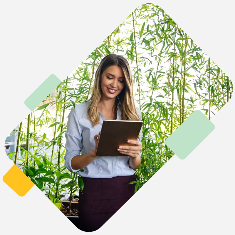 Mujer feliz viendo su tablet en un lugar lleno de plantas