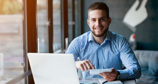 Hombre joven sonriendo programando sus pagos