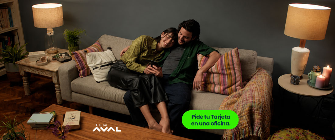 Pareja feliz en sofá solcitando su compra de cartera de Banco Popular