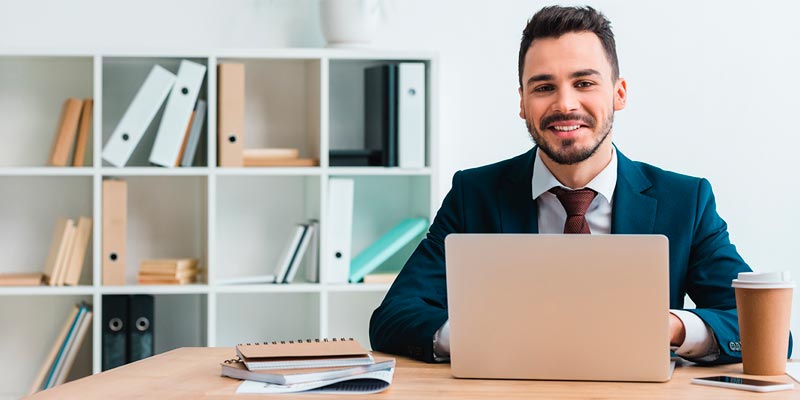 Hombre joven de traje azul consultando la información del estado y movimientos de su cuenta desde su lapotop