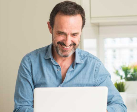 Hombre adulto con barba y camisa azul frente a su ordendor