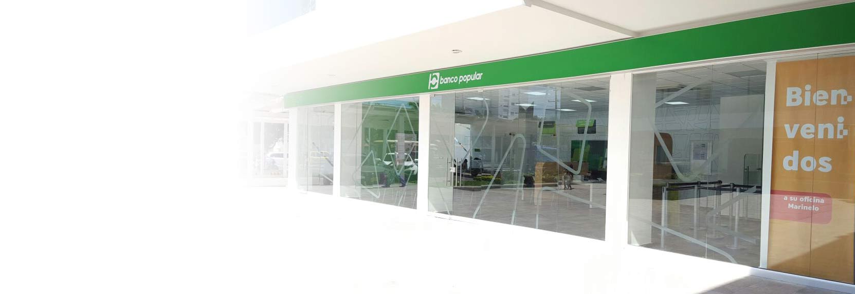 oficinas del Banco Popular con vidrios de cristal y letrero verde con logotipo blanco
