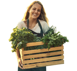 Una granjera sonriendo con una caja de alimentos frescos