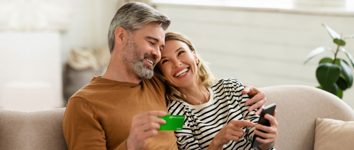 Pareja de personas maduras mirando una tablet y con la tarjeta de crédito del banco Popular
