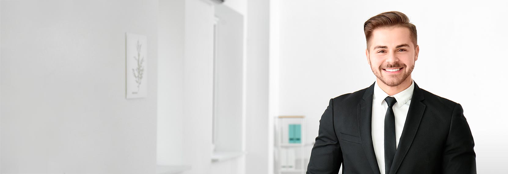 Hombre joven con barba de traje negro, camisa blanca y corbata sonriendo