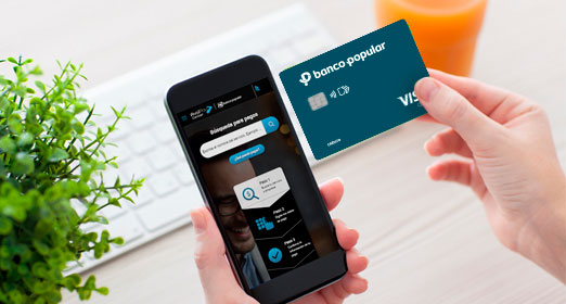 una persona con su tarjeta de debito en mano revisando el celular