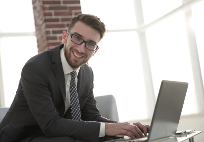 Hombre joven de traje formal frente a su laptop