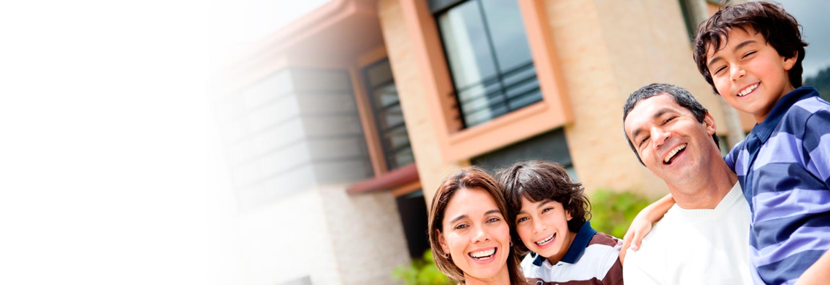 Una pareja con sus dos hijos felices frente de su casa nueva