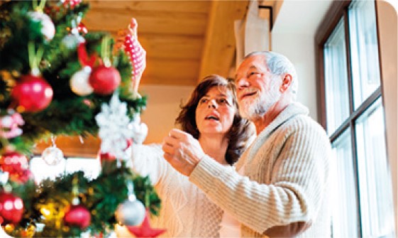 Pareja de adultos mayores decorando su arbol de navidad