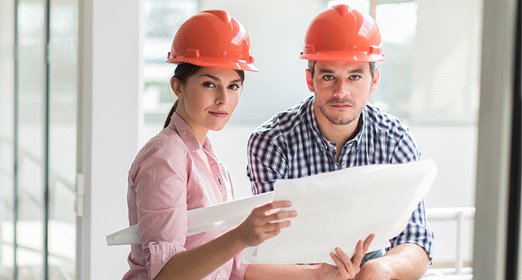 Una pareja de contructores con el plano de una edificación