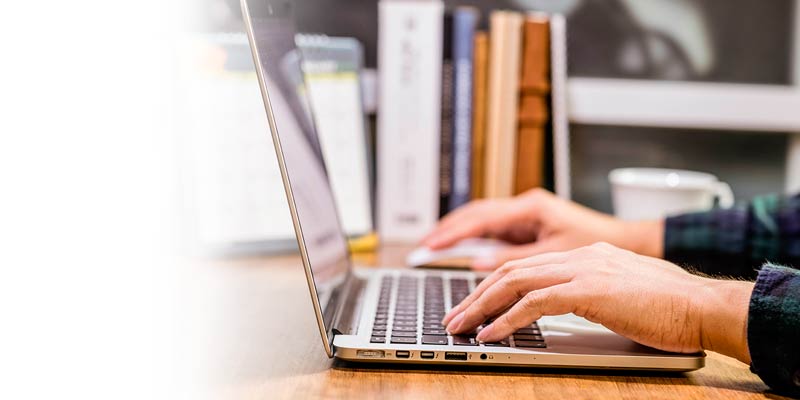 Primer plano de las manos de una persona ingresando sus datos desde su computador portátil