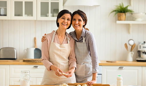 Madre e hija abrazadas y sonrientes cocinando juntas