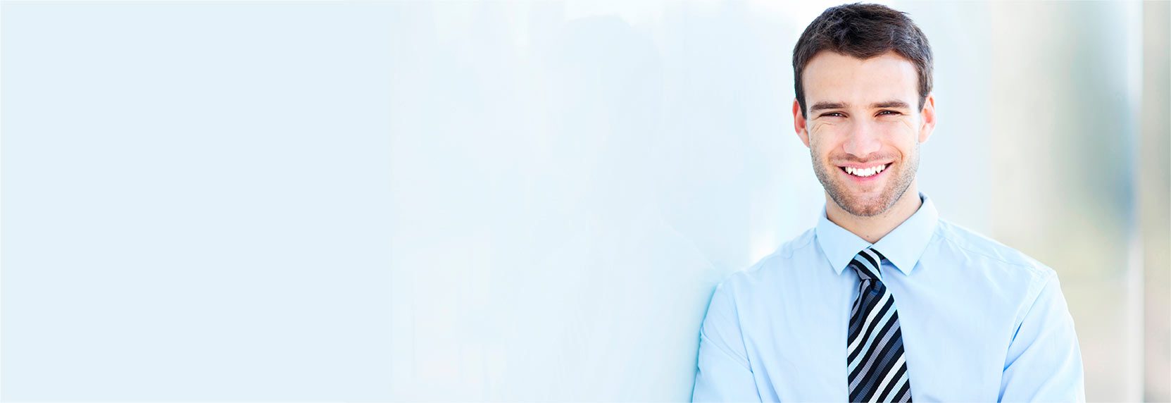 Un hombre joven con camisa azul y corbata sonriendo