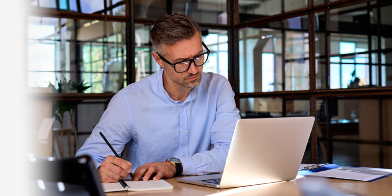 Un microempresario dentro de su propio negocio frente a su laptop