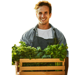 Un granjero sonriendo con una caja de alimentos frescos