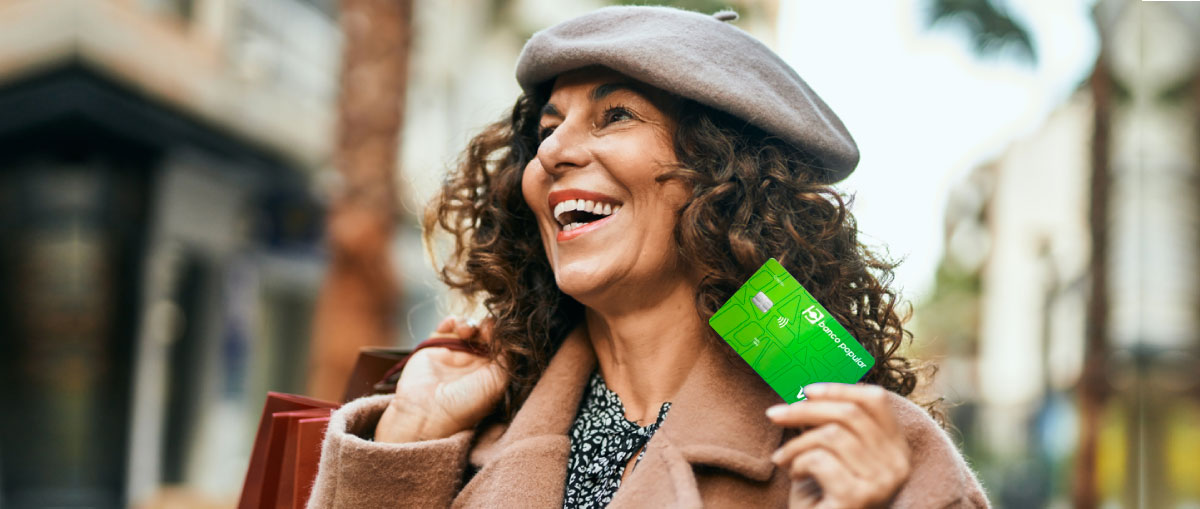 Mujer con su bolsa de compras y su tarjeta de crédito del banco popular