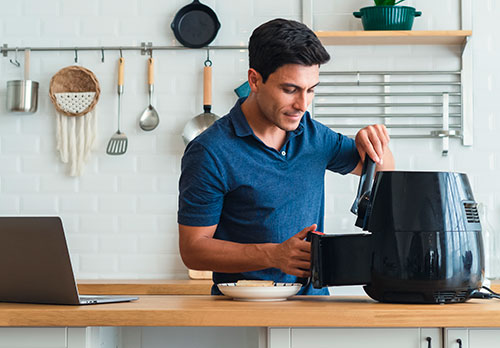 Imagen de hombre sonriendo usando un electrodomestico de su hogar
