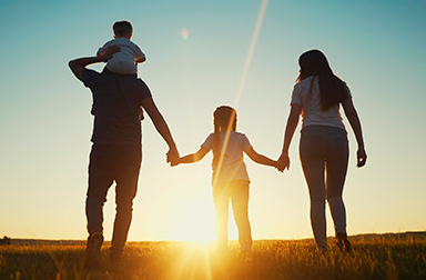 Pareja con sus dos hijos, caminando hacia el atardecer