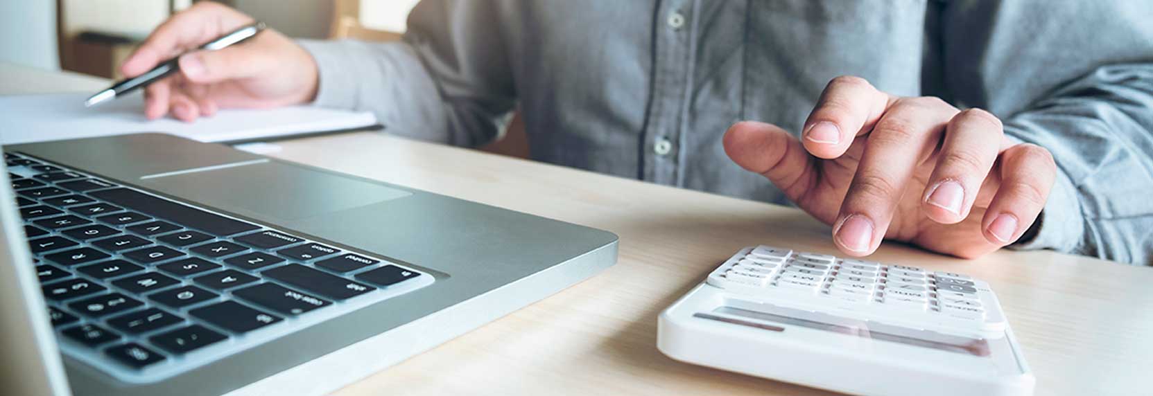 Primer plano de mano de un hombre sobre calculadora - llevando las cuentas para el pago de sus impuestos