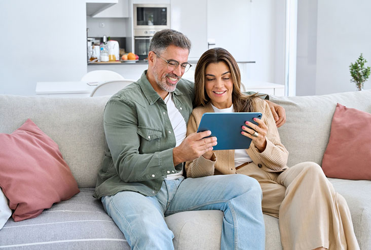 Pareja de personas mayores viendo su laptop snetados en el sofa