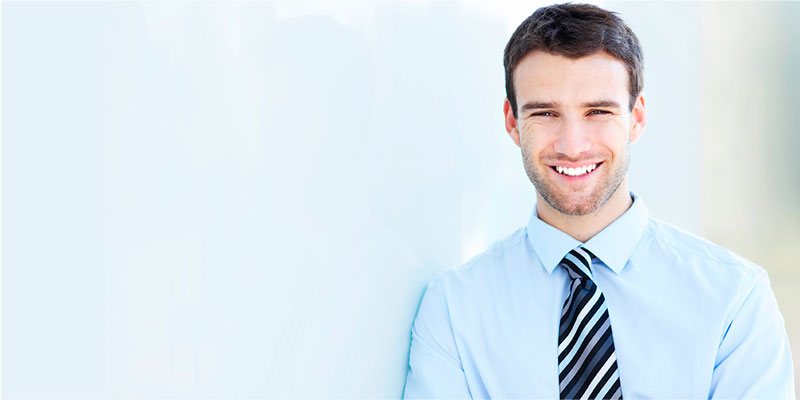 Un hombre joven con camisa azul y corbata sonriendo
