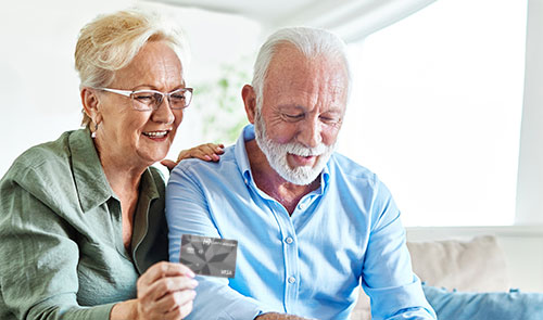 Hombre y Mujer mayores viendo una tarjeta del Banco Popular
