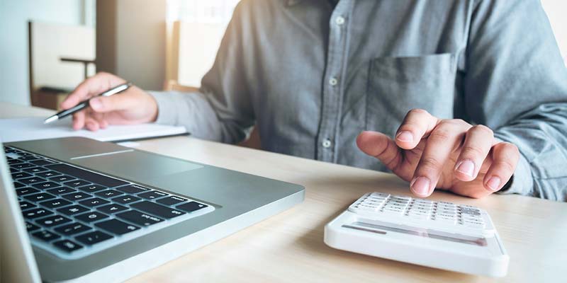 Primer plano de mano de un hombre sobre calculadora - llevando las cuentas para el pago de sus impuestos