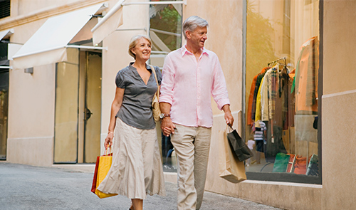 Pareja de personas mayores de 50 años paseando con bolsas de compras