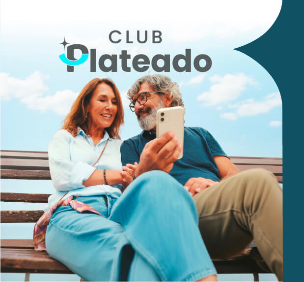 Hombre y mujer de edad adulta snetados en una banca de parque con su celular
