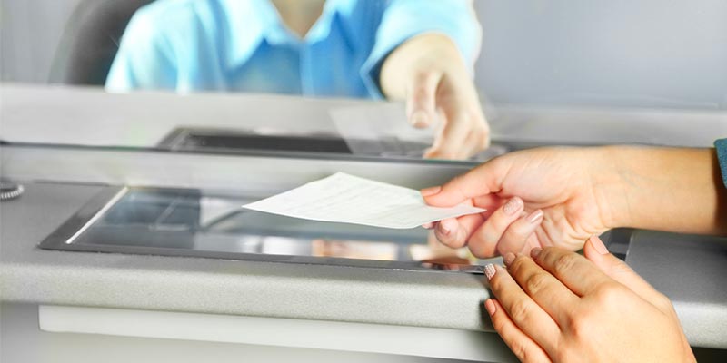 Manos de mujer realizando un pago con un número de validación de pago o PIN en ventanilla del Banco Popular