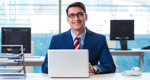 Un joven empresario con saco azul y corbata, accediendo al pago de la seguridad social PILA desde su computadora